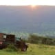 Safari vehicle parked on grassland overlooking vast valley at sunrise in Kenya