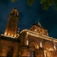 Illuminated historic church with tall bell tower and ornate stone facade at night in the Philippines
