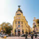 Metropolis Building in Madrid, Spain, a yellow ornate early 20th century landmark with a winged statue on top, surrounded by 
