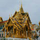 Grand Palace Bangkok with ornate golden spires, tiered roofs, and intricate Thai temple architecture under blue sky