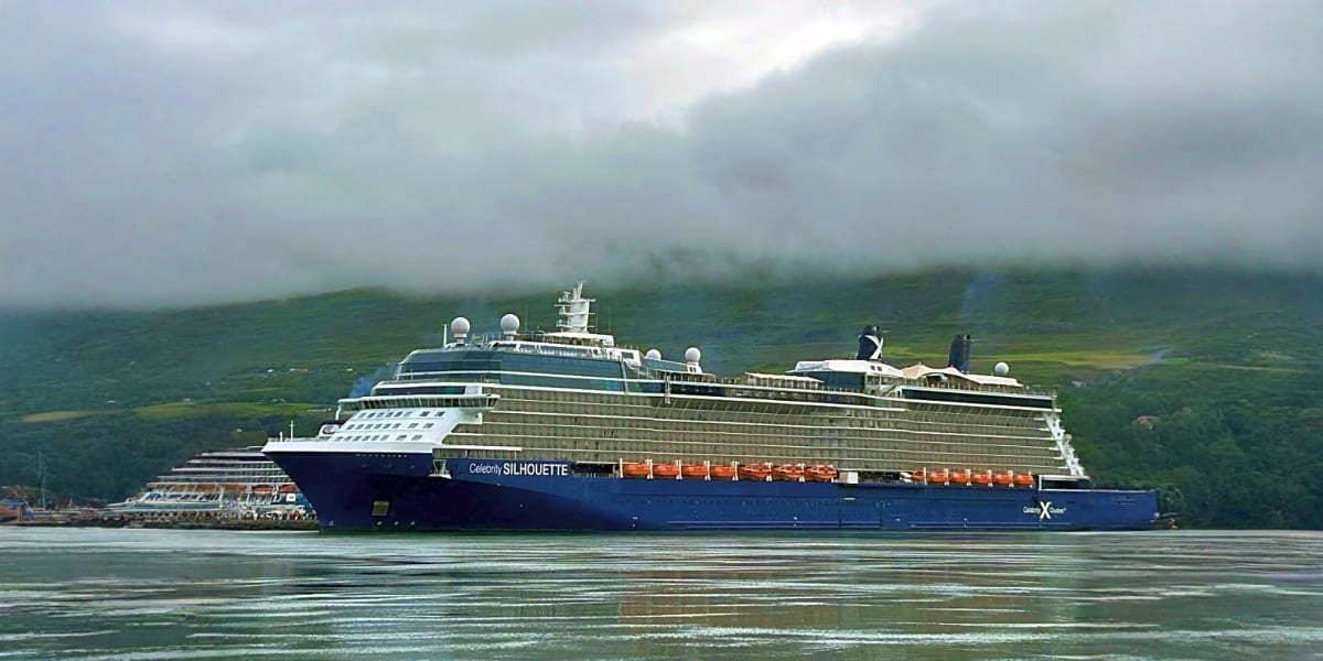 Celebrity Silhouette cruise ship docked in coastal waters with forested mountains in background