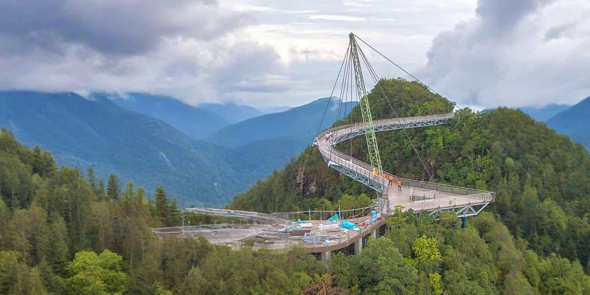 Langkawi Sky Bridge curved walkway suspended high above forested mountains with cable car station and valley views below
