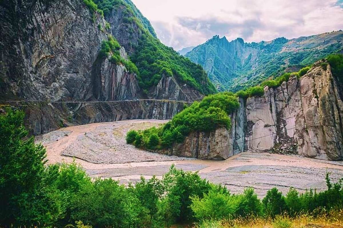 Scenic mountain gorge with steep rocky cliffs, lush green vegetation, and a winding river valley in Gabala