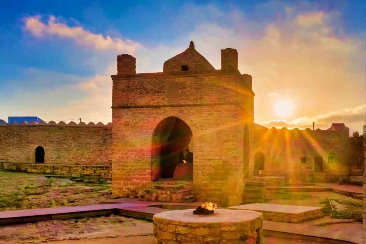 Ancient Ateshgah fire temple with arched entrance and chimneys illuminated by sunset in Absheron, Azerbaijan