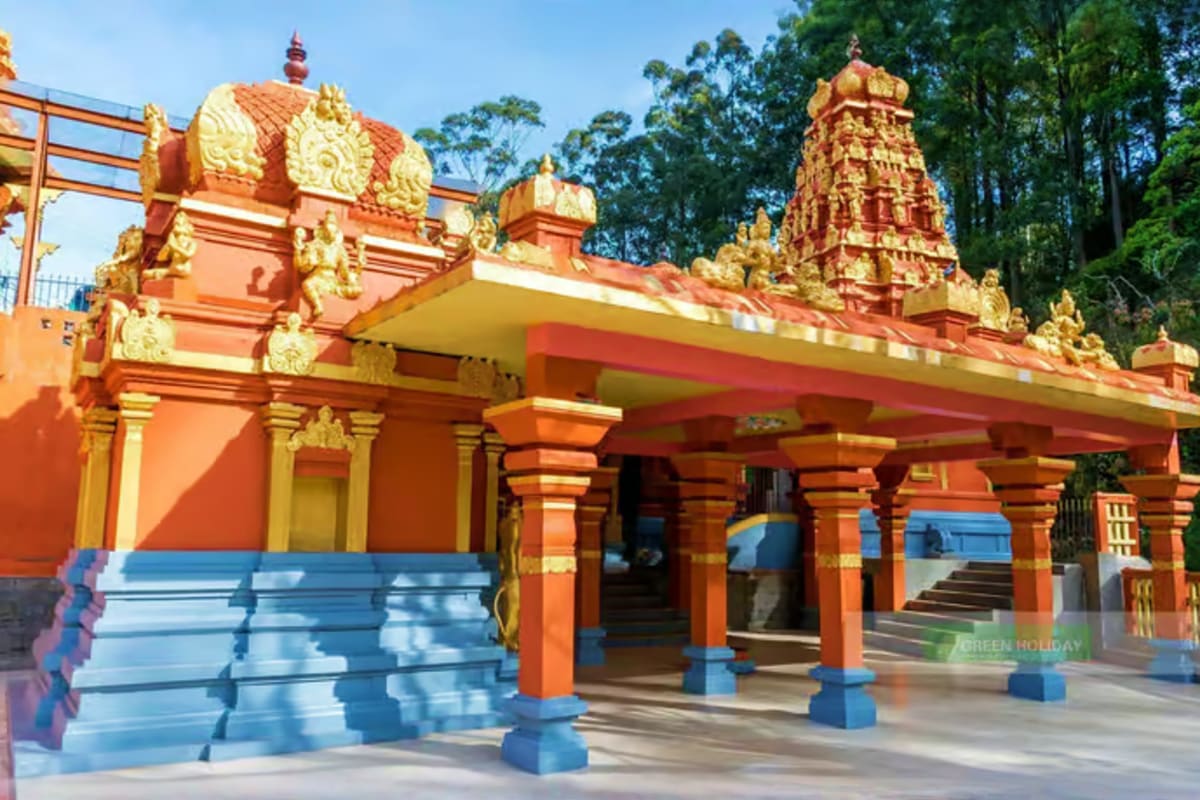 Hindu temple with ornate red and gold architecture, decorative pillars, and golden spires surrounded by tall trees