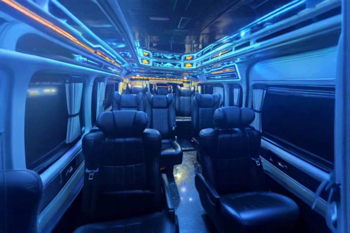 Modern intercity transfer bus interior with blue ambient lighting, black leather seats, and wide windows for passenger comfor