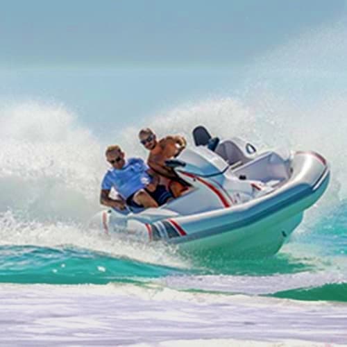 Group of people riding in a speedboat through ocean waves at a beach