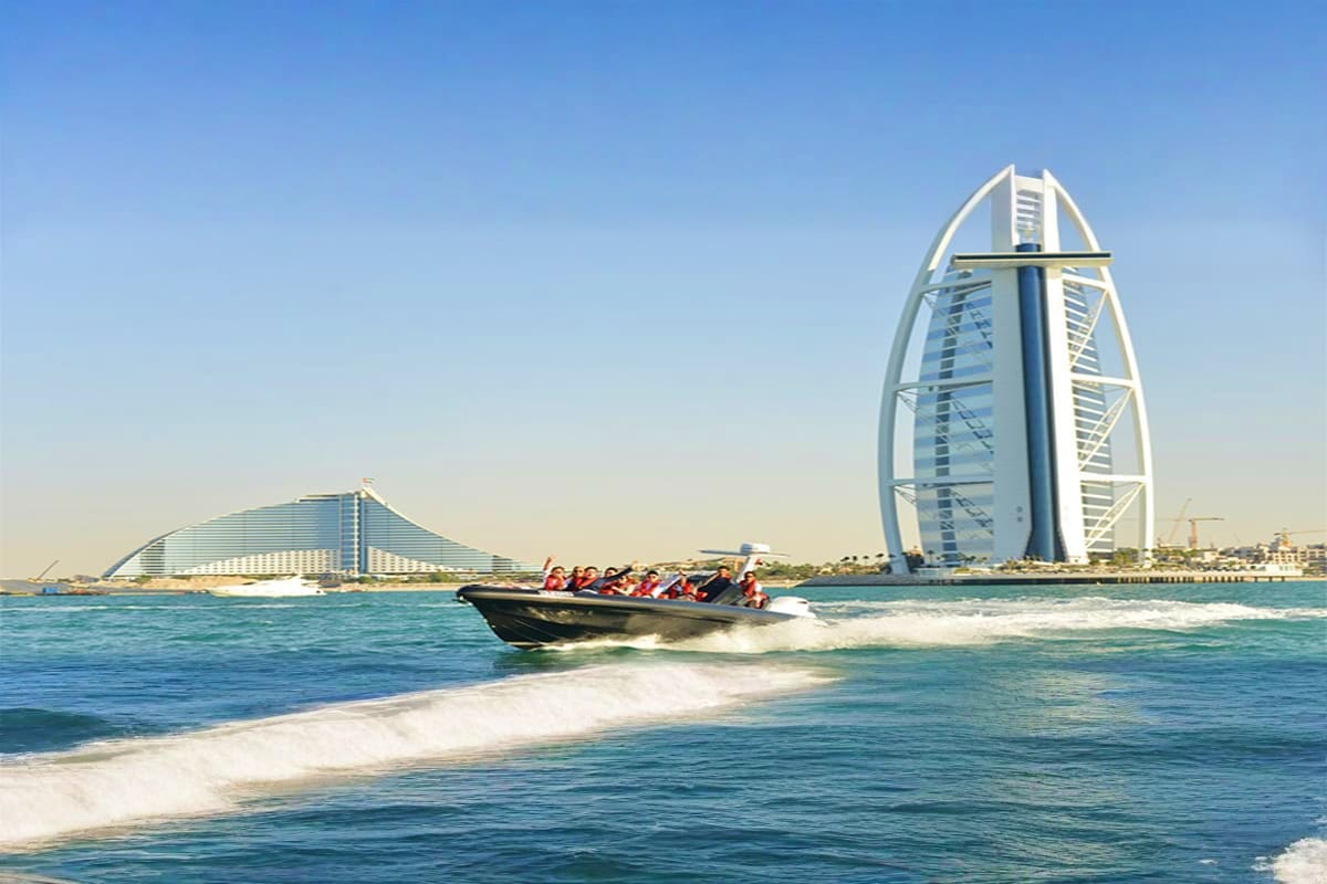 Speedboat tour passing Burj Al Arab luxury hotel in Dubai with passengers on board and Arabian Gulf waves