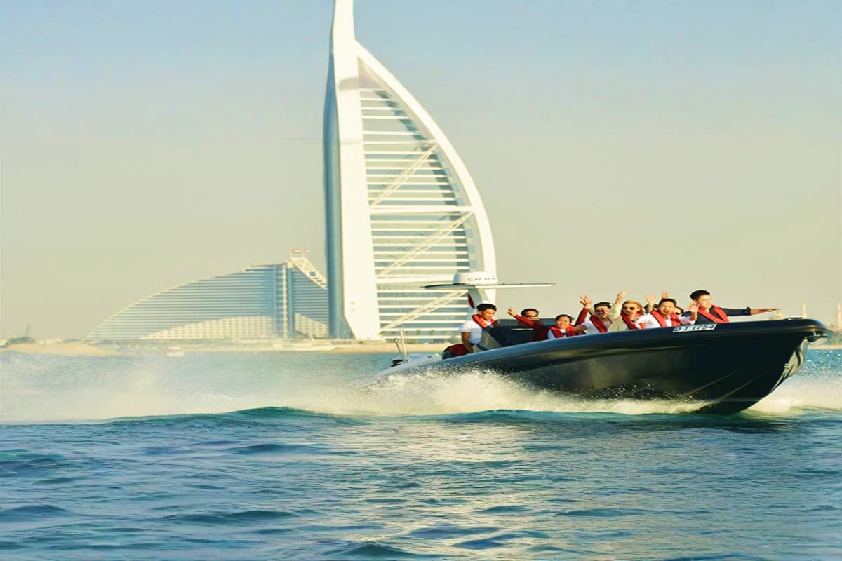 Group of tourists on a black speedboat in Dubai waters with the Burj Al Arab hotel visible in the background