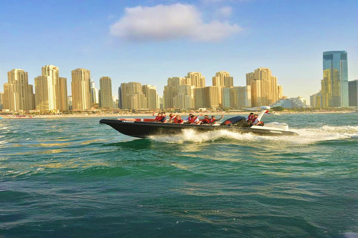 Black Boat Tours Black speedboat with passengers riding through ocean waves with San Diego high-rise hotel buildings skyline in background
