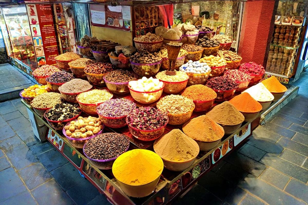 Colorful spice and ingredient display at traditional Dubai market stall with bowls of spices, nuts, and dried goods