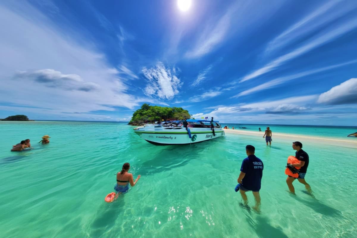 Tourists swimming and wading in turquoise water near a speedboat with James Bond Island's distinctive tree-covered rock forma