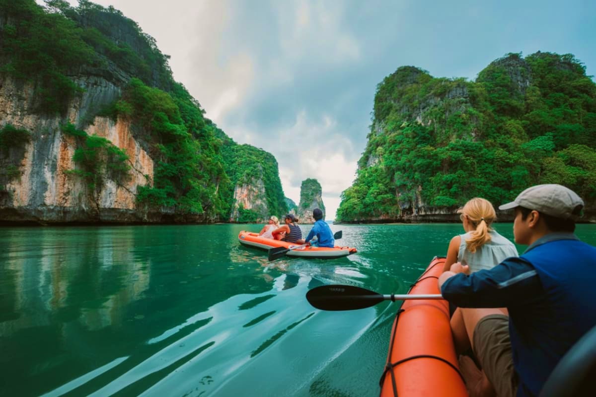 Tourists kayaking in turquoise waters between towering limestone cliffs at James Bond Island in Thailand