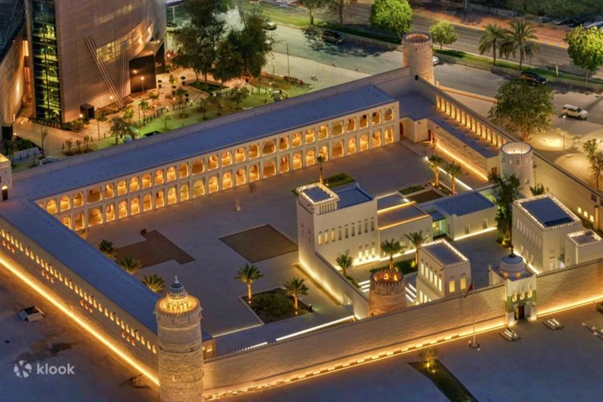Aerial night view of illuminated Qasr Al Hosn fortress with courtyard, towers, and traditional architecture in Dubai