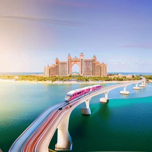 The Palm Monorail Monorail train crossing bridge over turquoise waters toward Atlantis The Palm resort hotel in Dubai