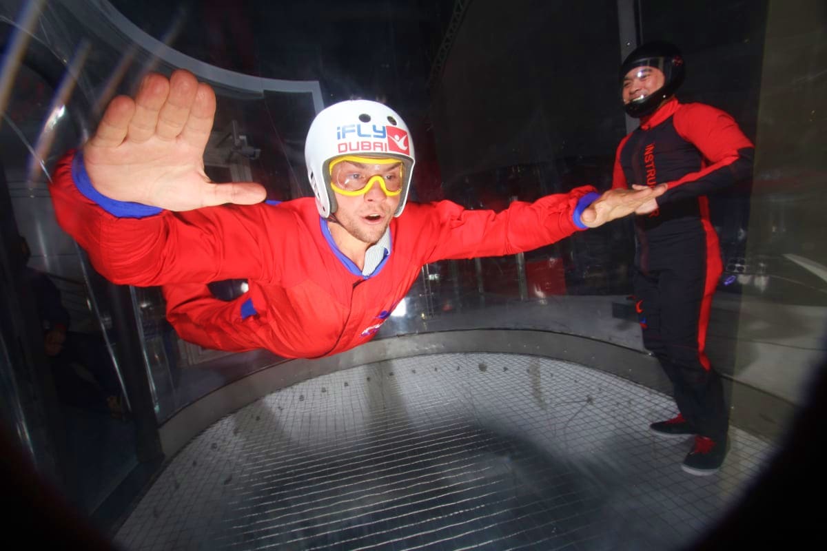iFly Dubai Man in red jumpsuit and white helmet indoor skydiving at iFly Dubai wind tunnel facility