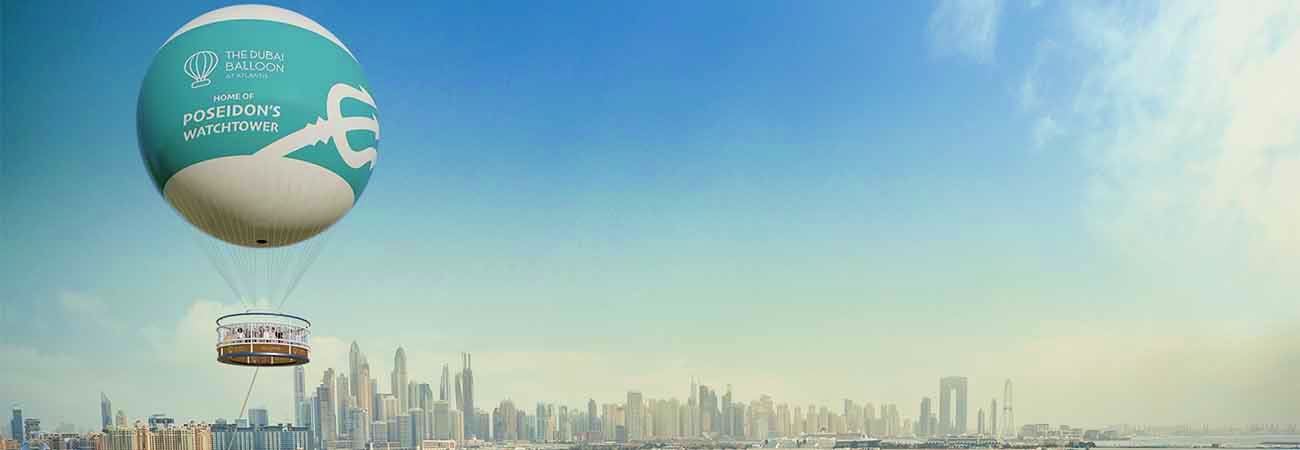 The Dubai Balloon tethered hot air balloon hovering above the Dubai skyline with Poseidon's Watchtower basket visible below