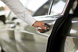 Person opening car door handle during nighttime airport transfer service