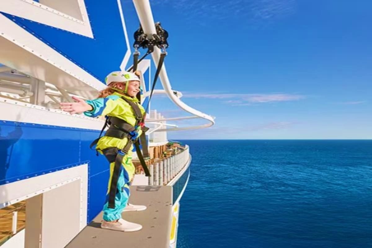 Child in yellow life jacket rappelling down side of cruise ship over ocean on Legend of the Seas