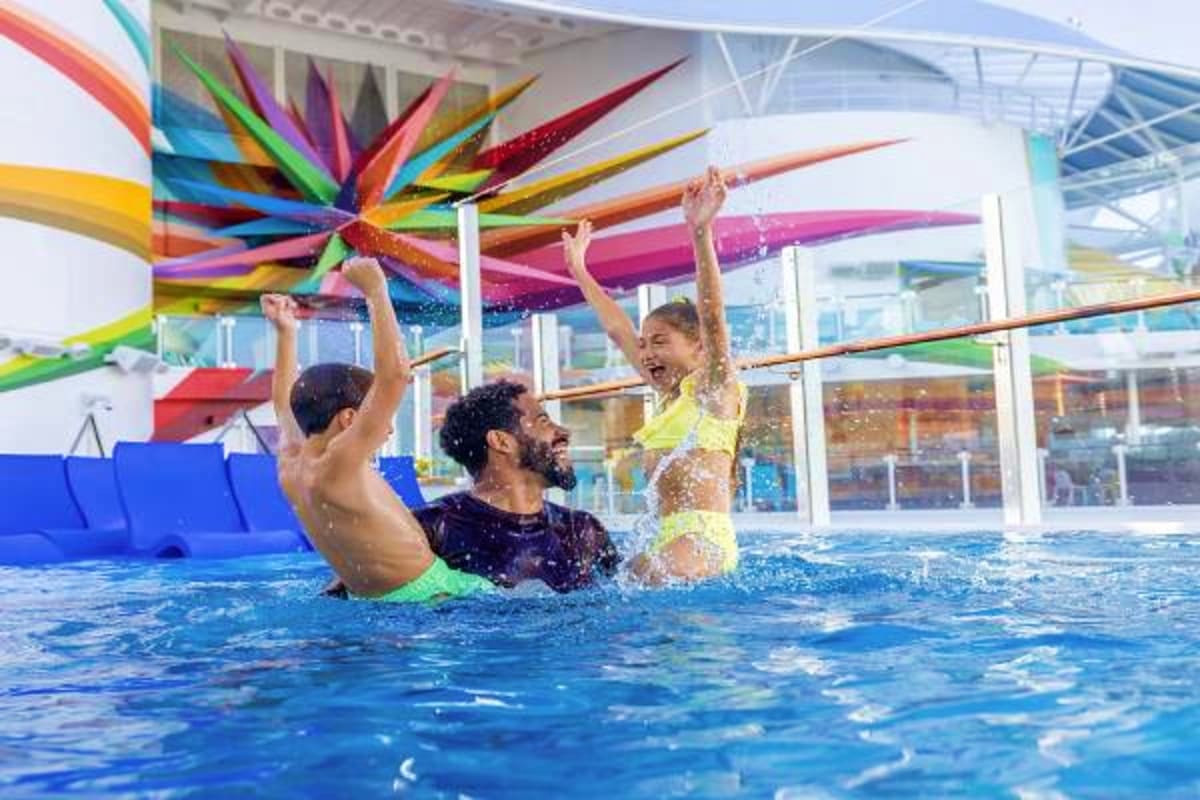 Father and two children playing in indoor swimming pool with colorful ribbon decoration overhead