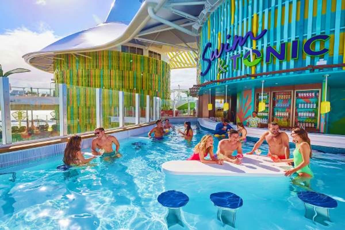 Indoor swimming pool on Legend of the Seas cruise ship with guests enjoying water activities and colorful bar area
