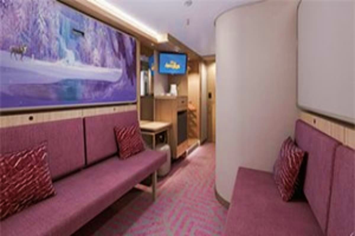Modern cruise ship interior cabin hallway with purple upholstered seating, curved walls, and digital displays