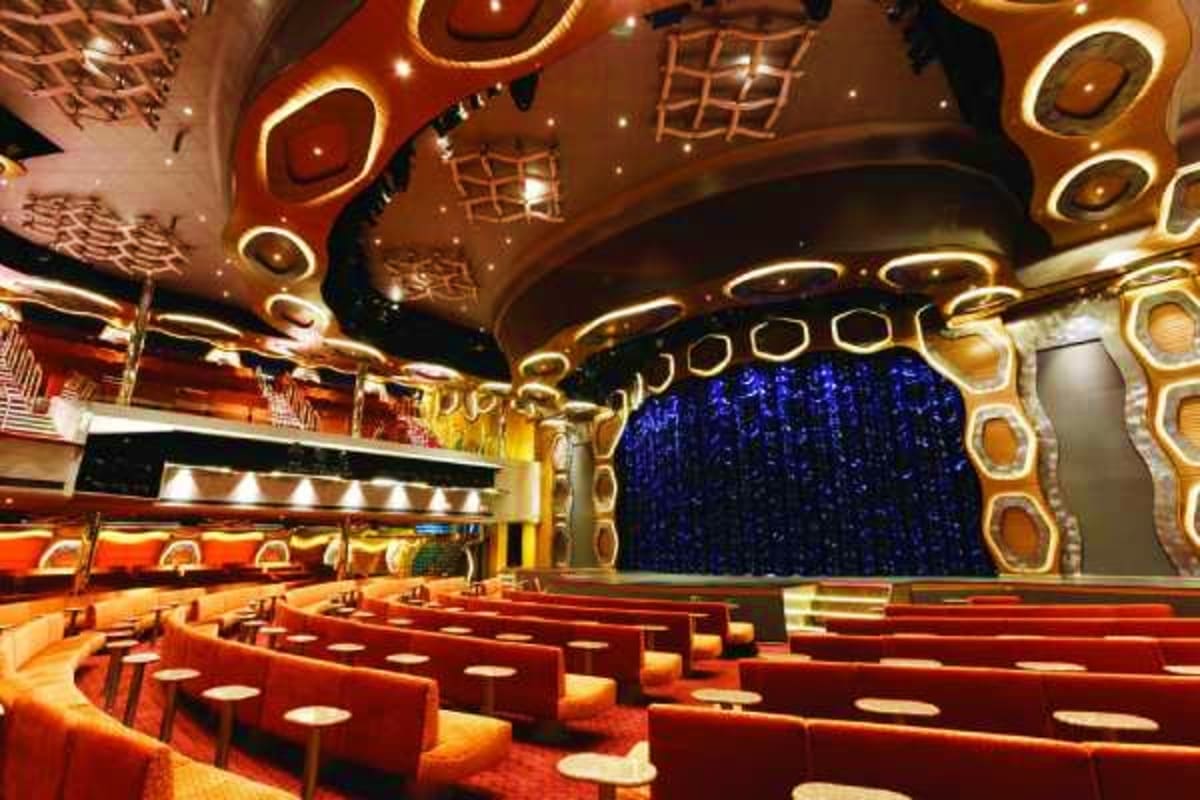 Luxurious theater interior with red velvet seats, ornate gold ceiling details, and blue curtain stage on Costa Diadema cruise