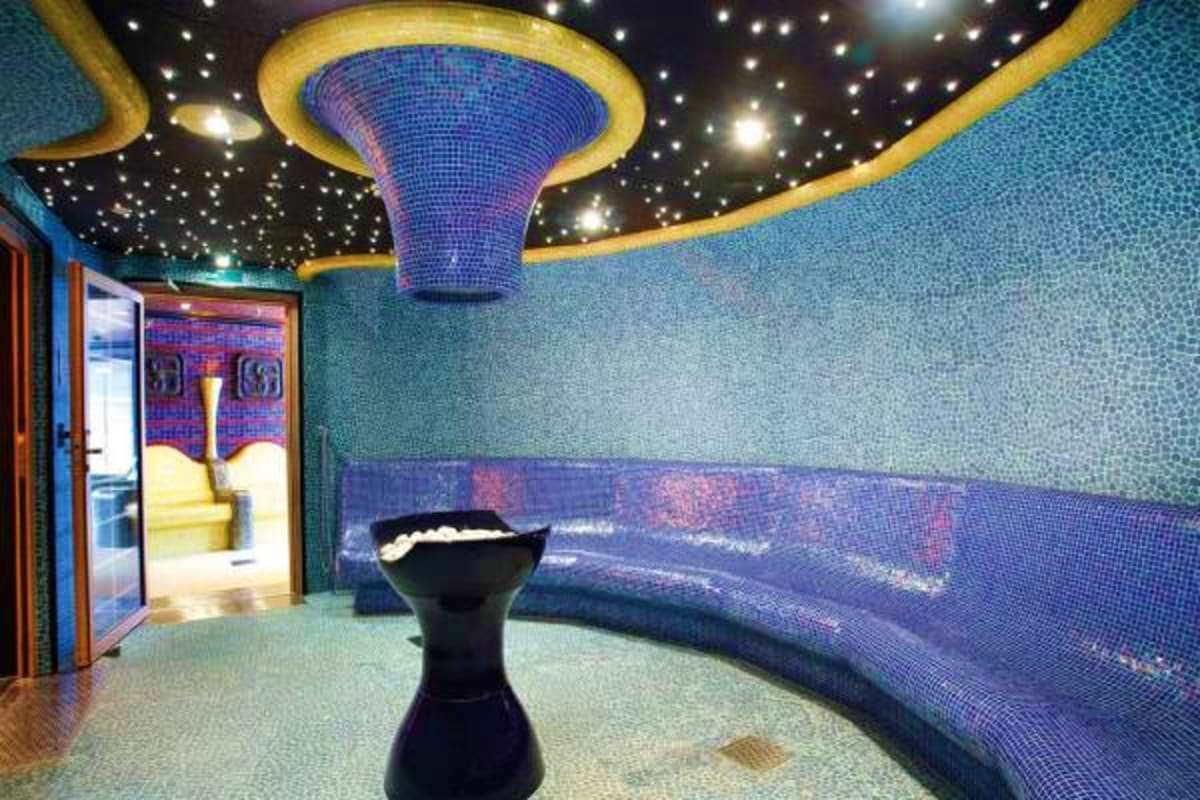 Luxurious spa interior with blue mosaic tile walls, illuminated ceiling with star lights, and curved seating area on cruise s