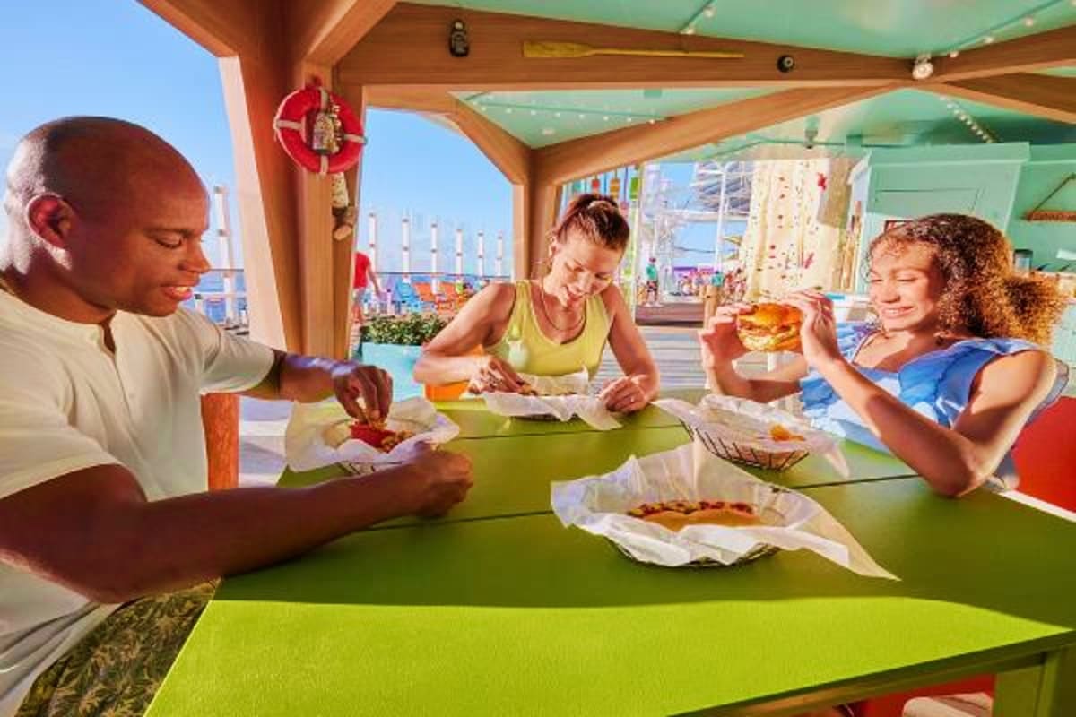 Family of three enjoying casual dining with burgers at outdoor deck restaurant overlooking Mediterranean ports