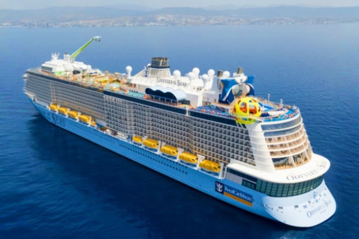Odyssey of the Seas cruise ship sailing in Mediterranean waters with coastal town visible in background
