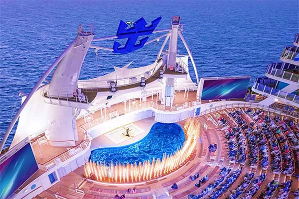 Legend of the Seas Barcelona Roundtrip Cruise Aerial view of Legend of the Seas cruise ship showing blue wave logo, swimming pool deck with lounge chairs, and ocean backdr