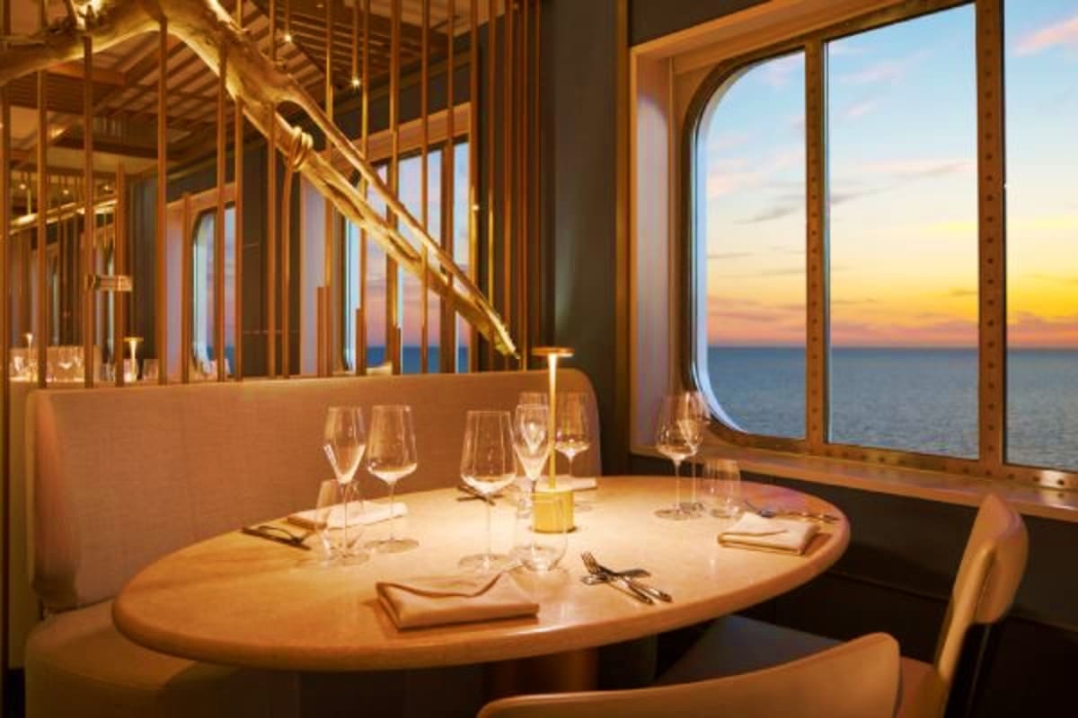 Elegant dining room with ocean sunset view through large windows on a cruise ship