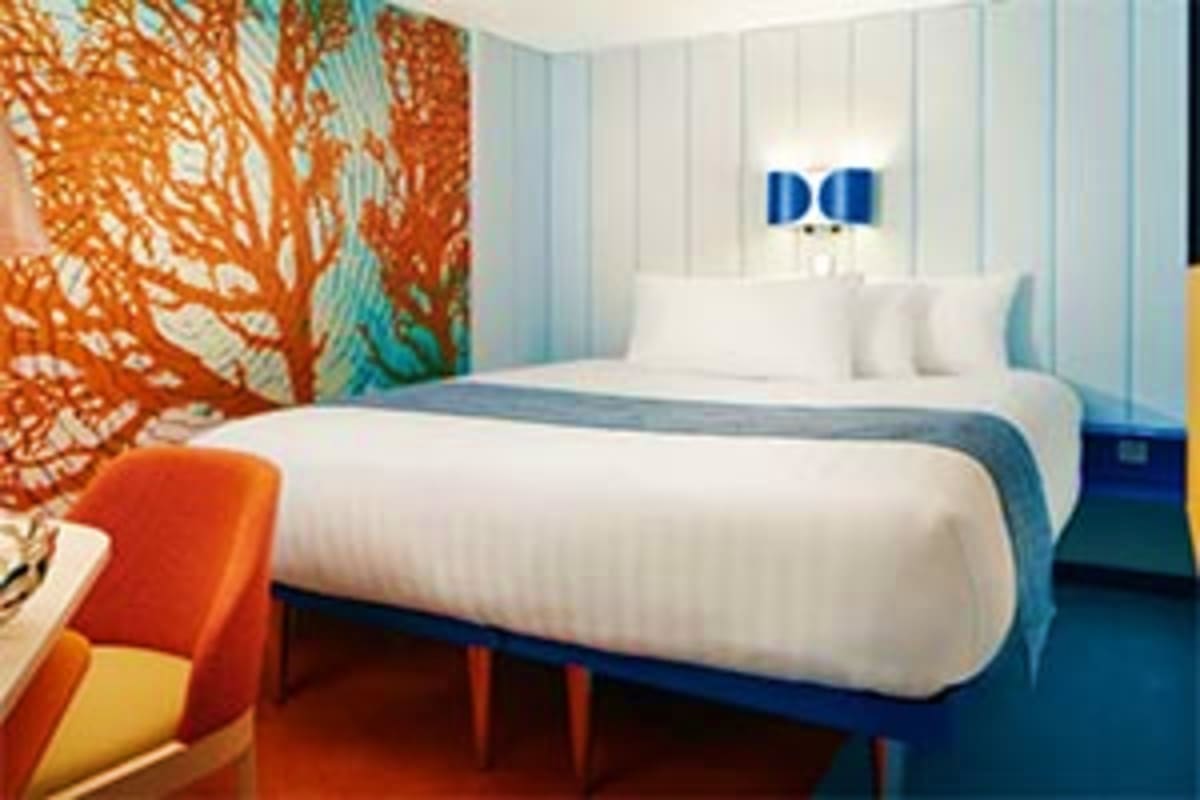 Costa Toscana Western Mediterranean Cruise Modern cruise ship cabin with cylindrical white bed, orange tree wallpaper accent, blue striped walls and nightstands