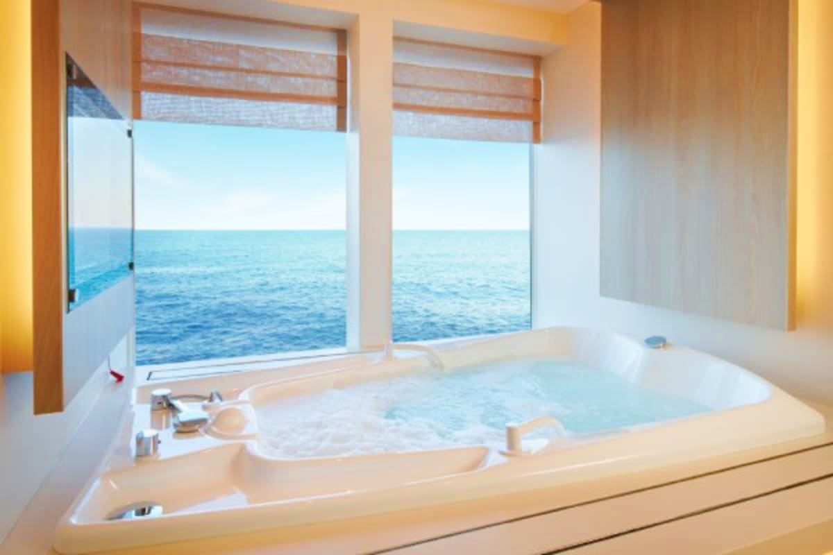 Costa Toscana Western Mediterranean Cruise Luxury bathroom with large whirlpool tub overlooking ocean view through floor-to-ceiling windows on Costa Toscana cruise ship