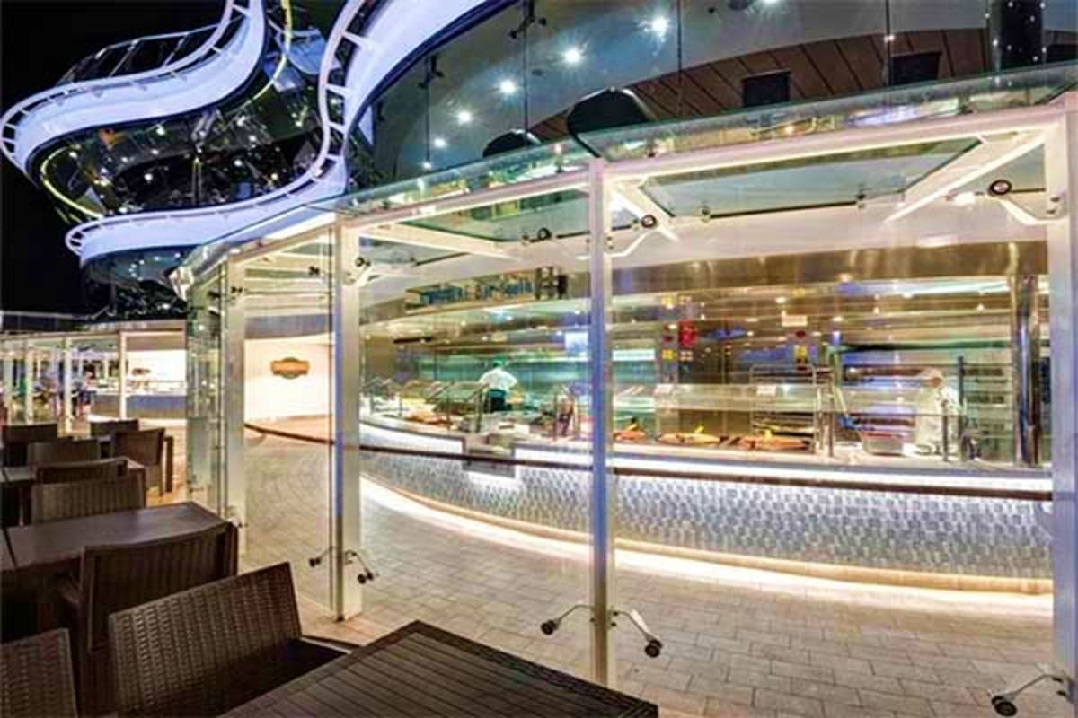 Modern cruise ship buffet restaurant with floor-to-ceiling windows, illuminated food display counters, and dining area at nig