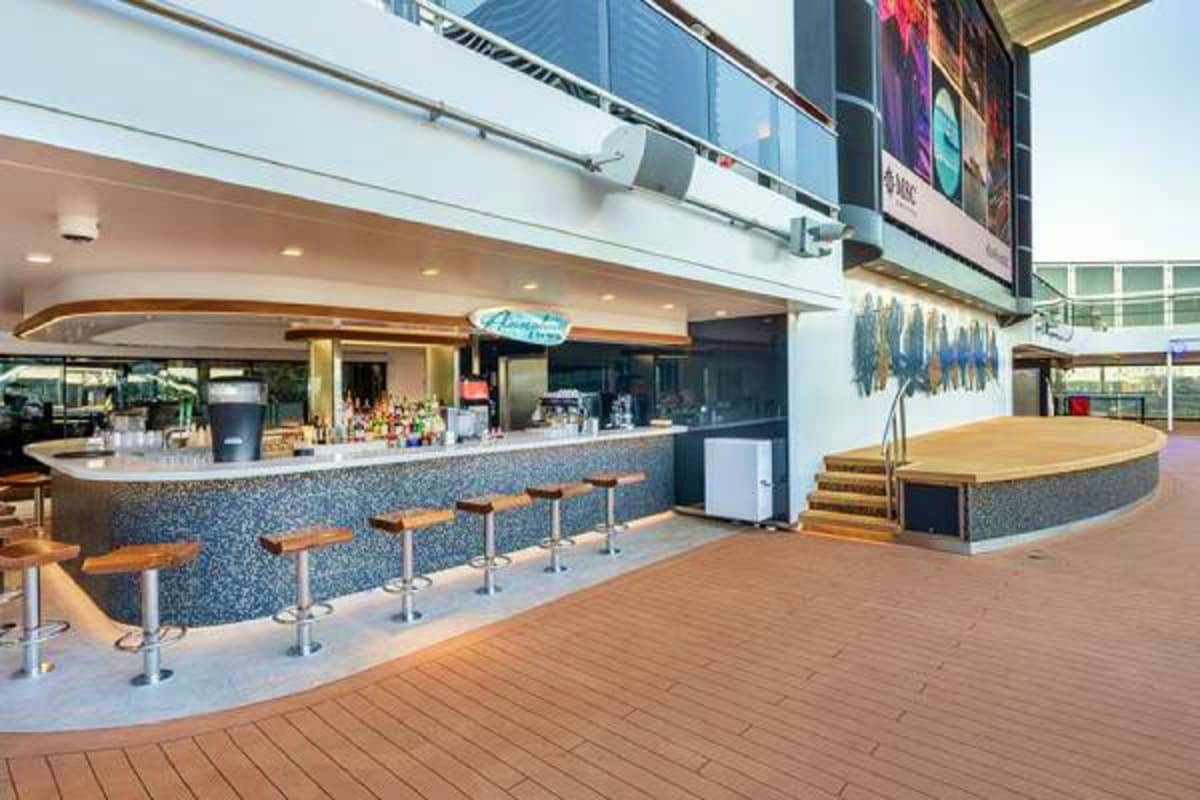 Modern cruise ship buffet bar with wooden bar stools, curved counter, and casual dining area on deck