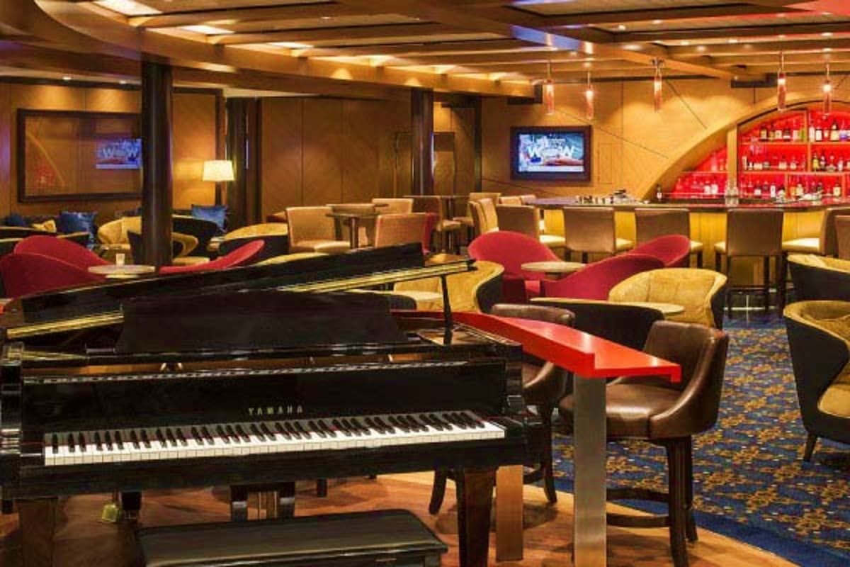 Luxurious cruise ship lounge with grand piano, upscale seating, bar, and warm golden lighting