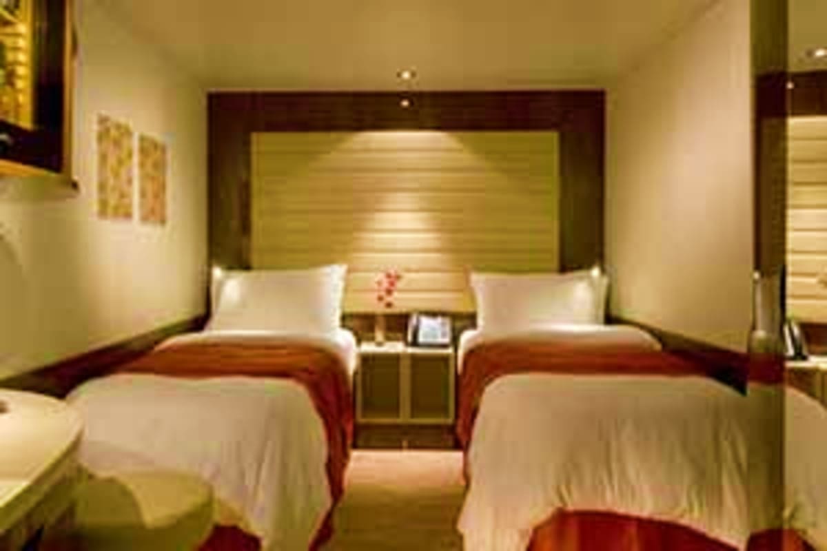 Norwegian Epic Southern Europe Cruise Modern hotel cabin with two twin beds, green headboard, white linens, and burgundy accents on Norwegian Epic cruise ship