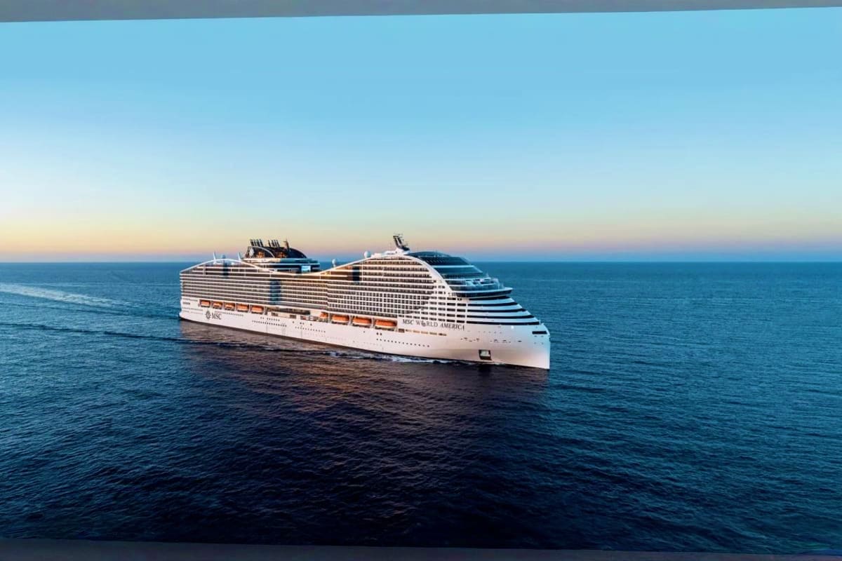 Large white MSC cruise ship sailing on blue ocean waters under clear sky at sunset