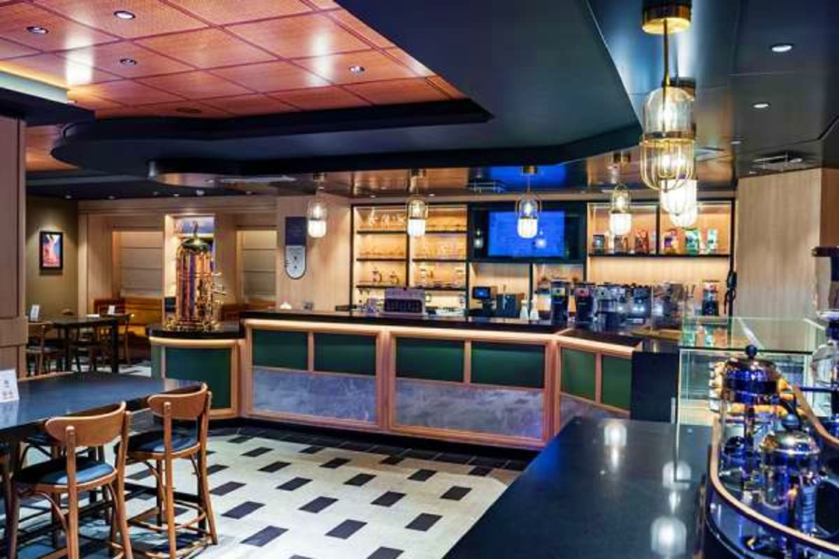 MSC World Europa Barcelona Roundtrip Cruise Modern cruise ship bar and lounge with green-paneled counter, wooden bar stools, pendant lighting, and black and white floor