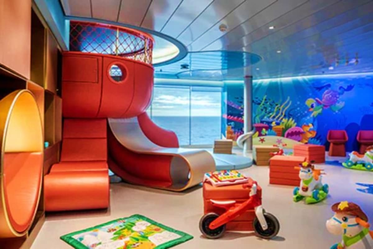 MSC World Europa Barcelona Roundtrip Cruise Modern cruise ship children's playroom with red slide, basketball hoop, toys, and ocean view through large windows
