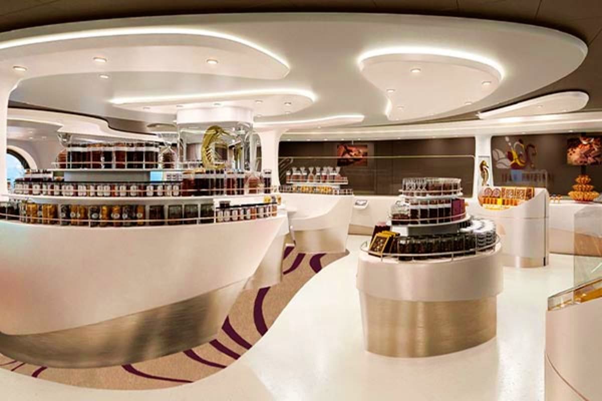 Modern luxury cruise ship interior showing white curved ceiling with LED lighting, tiered bar counter with bottles, and conte