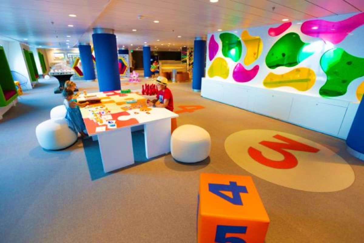 Colorful children's play area on Navigator of the Seas with interactive activities, giant number shapes, and blue support col