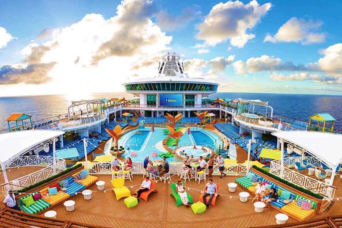 Aerial view of Navigator of the Seas cruise ship pool deck with swimming pools, lounge chairs, and passengers under blue sky