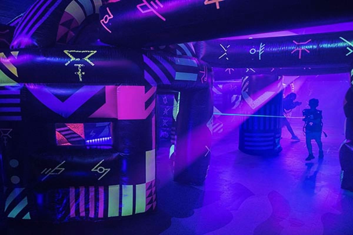 Futuristic neon-lit arcade game room with purple and pink lighting, glowing signage, and silhouettes of people gaming on Navi