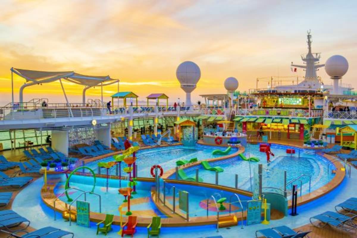 Colorful waterpark and pool deck on Navigator of the Seas cruise ship at sunset with water slides and loungers