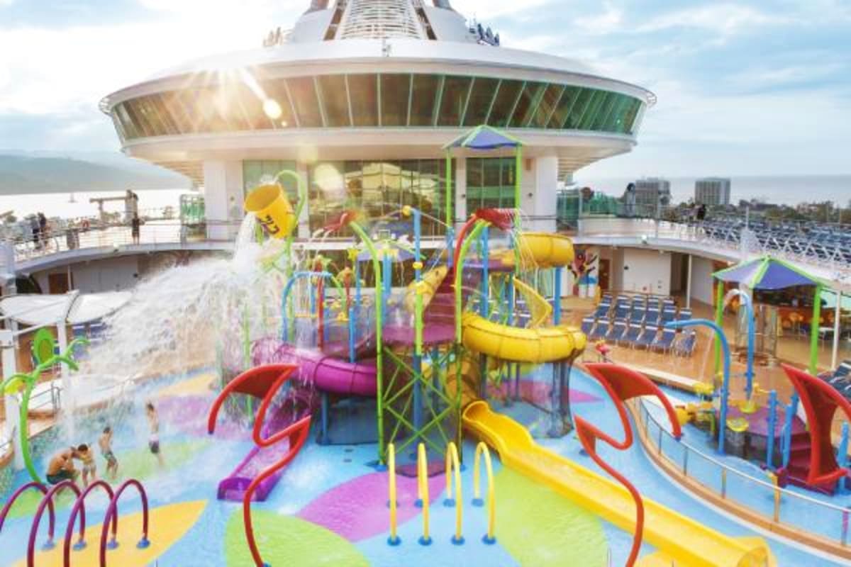 Colorful children's water park and play area on Liberty of the Seas cruise ship deck with ocean and coastline visible in back