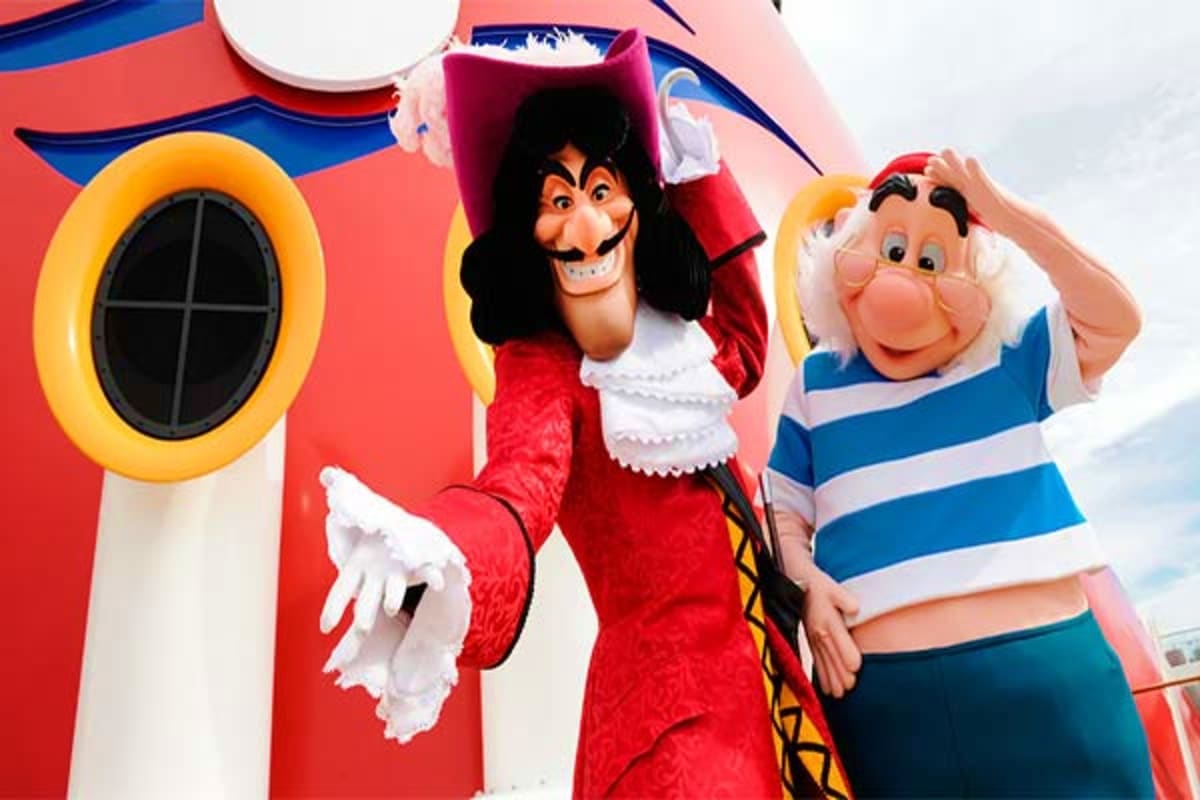 Captain Hook and sailor character mascots posing in front of colorful Disney Dream cruise ship facade with porthole window