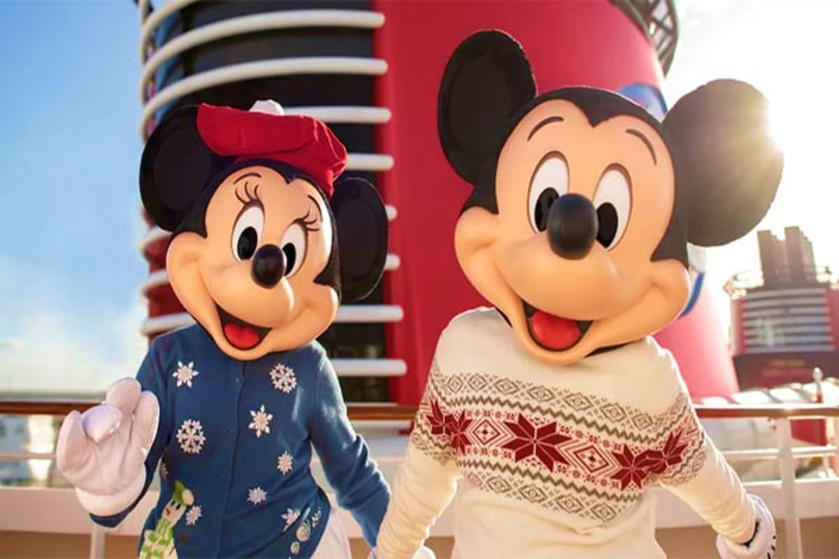 Mickey and Minnie Mouse in winter clothing on Disney Dream cruise ship deck with red funnel visible in background