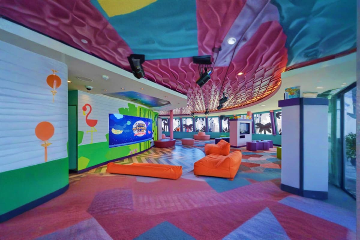 Colorful children's play area on Genting Dream cruise ship with orange bean bags, wave-patterned ceiling, and interactive ent